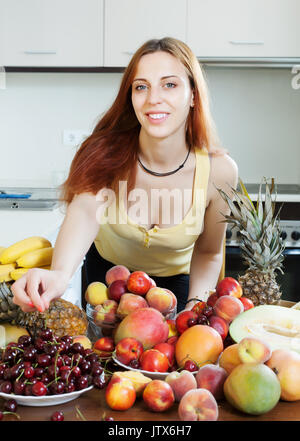 Femme positive avec tas de fruits mûrs pour cuisine Banque D'Images