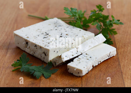 Bloc de tofu aux herbes naturelles, deux tranches de tofu et de persil sur planche en bois. Banque D'Images