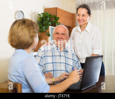 Hauts smiling couple répondre aux questions d'un travailleur social à la maison. L'accent sur l'homme Banque D'Images