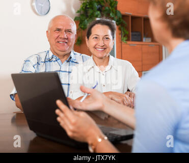 Répondre aux questions d'âge mûr de travailleur avec laptop in home Banque D'Images