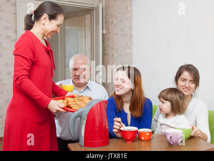 Famille multigénérationnelle communiquer sur un plateau avec des gâteaux à la maison Banque D'Images