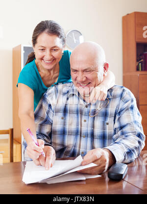 Happy mature couple reading documents financiers en home Banque D'Images