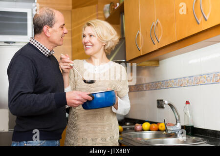 Happy smiling senior époux la préparation de délicieux repas dans une cuisine moderne. Focus on woman Banque D'Images