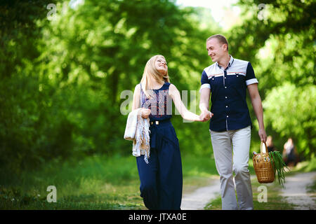 Couple going on picnic. fille blonde en robe bleu foncé avec motif à carreaux et l'homme à la lumière à l'intérieur avec panier en osier. famille heureuse relation concept Banque D'Images