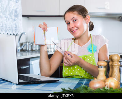 Smiling young woman shopping list en cuisine domestique Banque D'Images