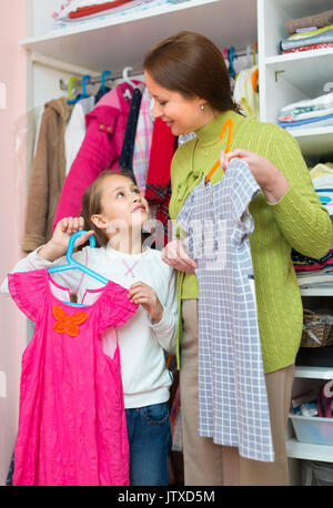 Enseignement femme heureuse petite fille pour prendre soin de vêtements Banque D'Images