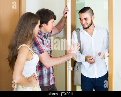 Couple sombre salutation cheerful young salesman in doorway Banque D'Images