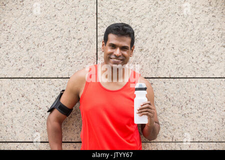 Portrait de l'homme Indien athlétique se reposant après ruissellement urbain à travers les rues de la ville. Asian male runner en tenant debout pause détente. Banque D'Images