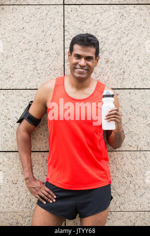 Portrait de l'homme Indien athlétique se reposant après ruissellement urbain à travers les rues de la ville. Asian male runner en tenant debout pause détente. Banque D'Images