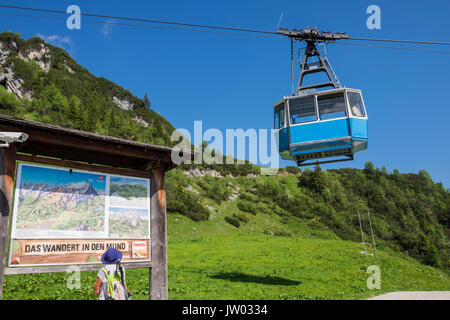 Panneau d'informations lecture femme walker comme Hochalmbahn cabine téléphérique descend la montagne,,, Zugspitzland Hochalm Kreuzeck, Bavière, Allemagne Banque D'Images