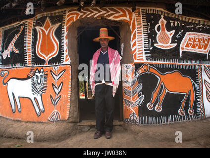 L'Éthiopie, Kembata Alaba, Kuito, éthiopien musulman avec un chapeau debout devant sa maison peinte traditionnelle Banque D'Images