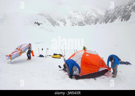 Les alpinistes sont de mettre en place des tentes dans un blizzard sur la partie inférieure du glacier Kahiltna sur Denali en Alaska. Banque D'Images