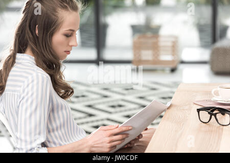 Vue latérale des concentrated businesswoman typing tout en travaillant dans un café Banque D'Images