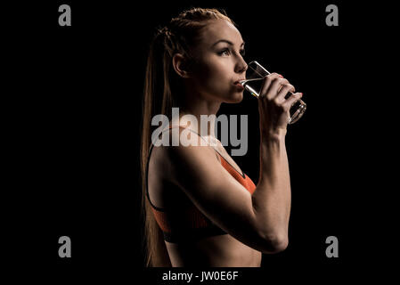 Jeune femme sportive l'eau potable à partir du verre et à l'écart Banque D'Images