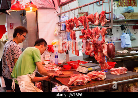 HONG KONG - le 7 juillet 2017 : un boucher découper un morceau de viande de porc pour un client dans un Shum Shui Po de la rue du marché à Hong Kong. Banque D'Images