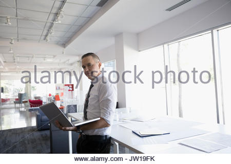 Portrait confiant male architect with laptop in open plan office