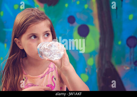 Belle petite fille boit de l'eau de bouteille en plastique Banque D'Images