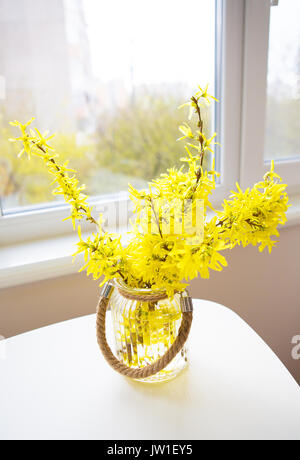 Un bouquet de fleurs jaunes dans un vase debout sur un tableau blanc Banque D'Images