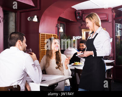Adultes ayant des conjoints souriant ce jour en classe moyenne restaurant. L'accent sur fille blonde Banque D'Images