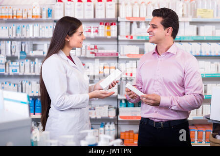 Souriante jeune femme pharmaceutist en pharmacie d'aide aux clients de choisir des médicaments Banque D'Images