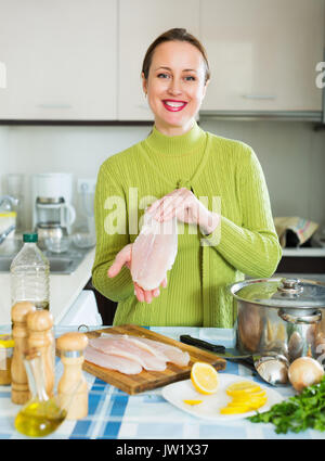 Smiling housewife cuisson de la soupe avec du poisson en filets à cuisine Banque D'Images