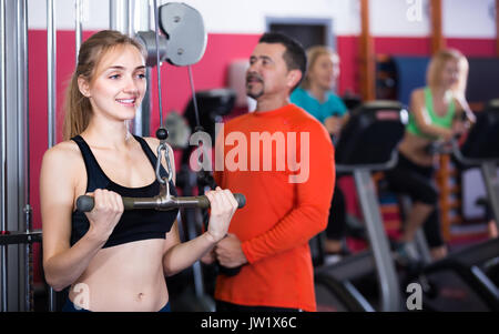 Femmes positives et l'homme ayant un entraînement intensif sur des machines de fitness club. Selective focus Banque D'Images