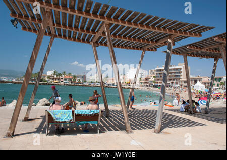 Les personnes bénéficiant de l'ombre offerte par la plage près de Portixol, Mallorca, Espagne Banque D'Images