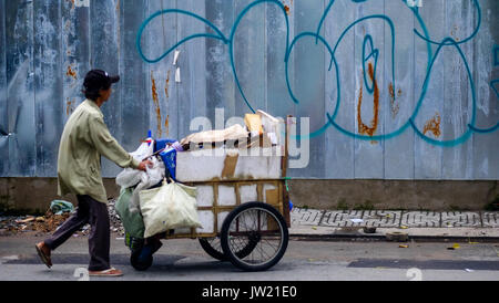 Un homme pousse un panier vietnamien le long d'une rue à Ho Chi Minh Ville, Vietnam Banque D'Images