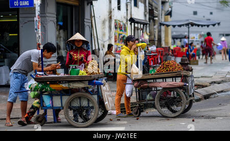 Les vendeurs de rue vietnamien femelle vendre le fruit de leurs chariots dans une rue à Ho Chi Minh Ville, Vietnam Banque D'Images