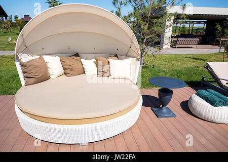 Close up chaise beige luxueux avec des oreillers sur plancher en bois à côté d'une piscine Banque D'Images