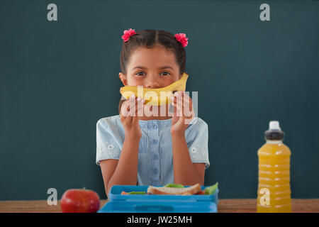 Girl holding banana à table contre chalkboard Banque D'Images