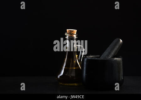 Mortier en granit pour les herbes et l'huile d'olive sur fond noir en sombre Banque D'Images