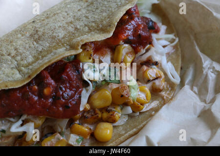 Libre de l'un des poissons colorés taco, faites à la main avec des tortillas de maïs remplis de maïs, choux, salsa, et la coriandre avec la lumière naturelle sur un wrapper de papier Banque D'Images