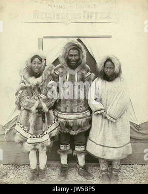 Eskimo homme et deux femmes debout devant le bureau de l'exploitation minière, de Port CLARENCE, Alaska, ca 1900 (HESTER 292) Banque D'Images