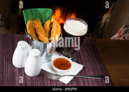 Un pub/restaurant/snack-déjeuner chaud et des filets de poulet panés épicé avec une trempette au Chili doux et un verre de bière. Banque D'Images