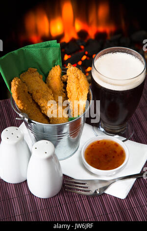 Un pub/restaurant/snack-déjeuner chaud et des filets de poulet panés épicé avec une trempette au Chili doux et un verre de bière. Banque D'Images