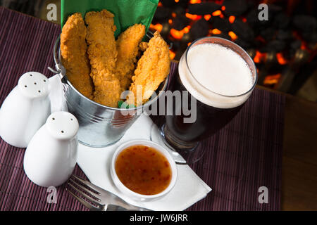 Un pub/restaurant/snack-déjeuner chaud et des filets de poulet panés épicé avec une trempette au Chili doux et un verre de bière. Banque D'Images