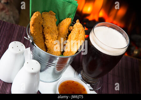 Un pub/restaurant/snack-déjeuner chaud et des filets de poulet panés épicé avec une trempette au Chili doux et un verre de bière. Banque D'Images