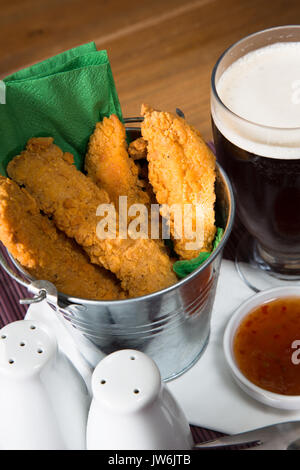 Un pub/restaurant/snack-déjeuner chaud et des filets de poulet panés épicé avec une trempette au Chili doux et un verre de bière. Banque D'Images