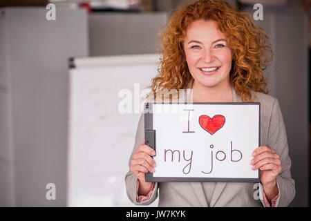 Red haired smiling businesswoman holding petite affiche. Banque D'Images