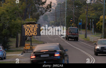 Un panneau à message variable les automobilistes d'avertissement de la fumée au-dessus de la route et un incendie moteur lors d'un brûlage de réduction des risques à Sydney Banque D'Images