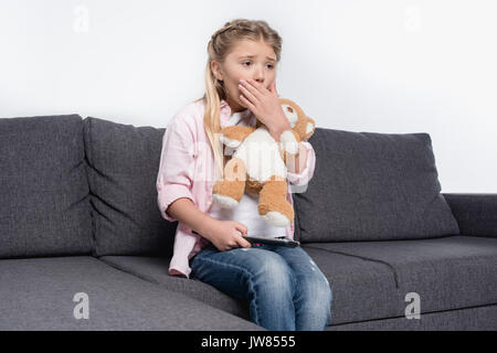 Petite fille aux ours peur tout en regardant la télévision isolated on white Banque D'Images