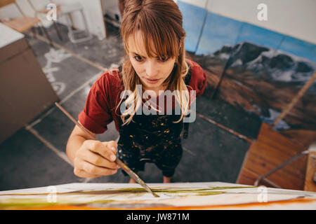Vue d'en haut photo de jeune femme peintre peinture photo en studio. Dessin femme peintre sur toile. Banque D'Images