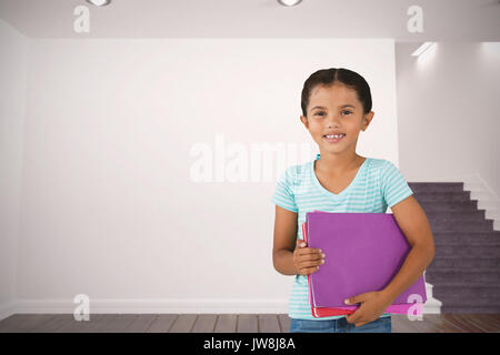 Portrait of smiling girl holding files contre chambre blanche avec escaliers Banque D'Images