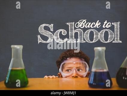 Digital composite of Student boy hiding derrière une table contre le tableau noir bleu avec texte retour à l'école Banque D'Images