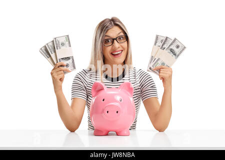 Cheerful woman derrière une table avec des paquets d'argent et une tirelire isolé sur fond blanc Banque D'Images