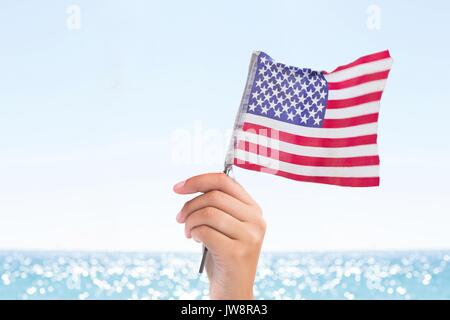 Digital composite de personne tenant un drapeau USA dans la plage Banque D'Images
