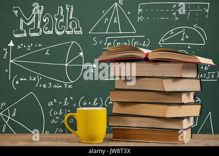 Composite numérique de livres sur la table contre green ardoise sur l'éducation et les graphiques Banque D'Images