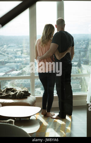 Vue arrière du couple hugging les uns les autres dans la salle de séjour à la maison Banque D'Images