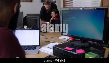 Collègues using digital tablet while working at desk in office Banque D'Images